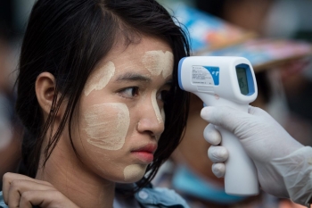 Ad una donna che indossa un trucco tradizionale del Myanmar viene misurata la febbre