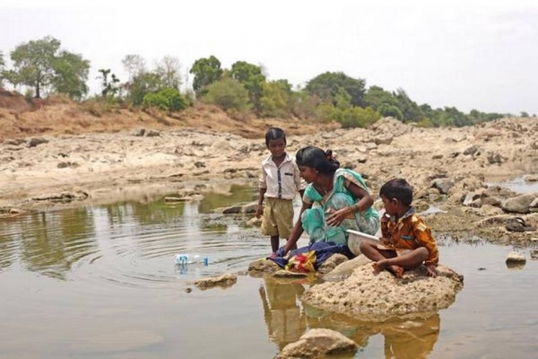 Mother and her children wash in river in Maharashtra, India