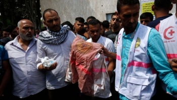 Il padre di Razan Al-Najjar mostra il suo camice insanguinato durante i suoi funerali