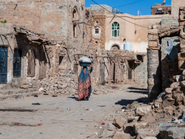 Donna che cammina con un canestro sulla testa in una strada deserta di Sanaa