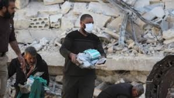 Le persone raccolgono attrezzature mediche trovate sotto le macerie di un ospedale nella provincia di Idlib
