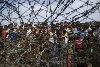Rohingya refugees behind a barbed-wire fence in the border zone between Myanmar and Bangladesh