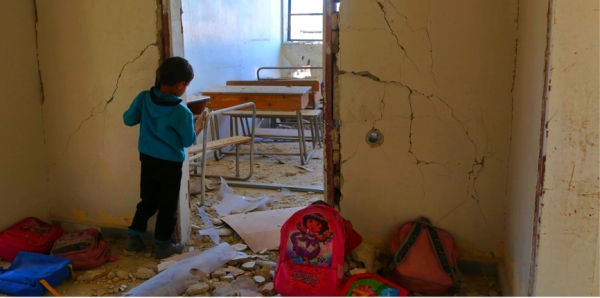 Un bambino siriano guarda l’aula di scuola distrutta nella città di Ulaya, vicino Damasco 
