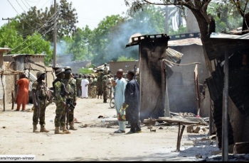  Soldati di fronte alle abitazioni bruciate dai terroristi di Boko Haram a Zabarmari, un villaggio di pescatori e agricoltori nei pressi di Maiduguri, nel nord-est della Nigeria, 3 luglio 2015.