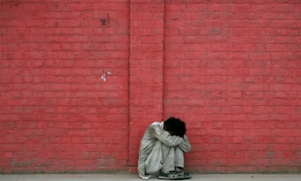A desperate man crying against a wall
