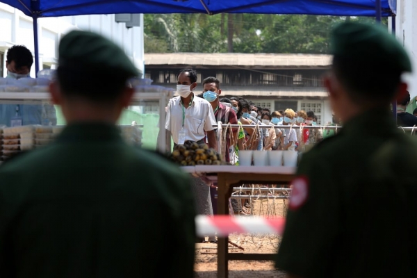 Distribuzione di cibo, sotto il controllo di soldati, in un campo militare usato per la quarantena, Yangon 9 aprile 2020.