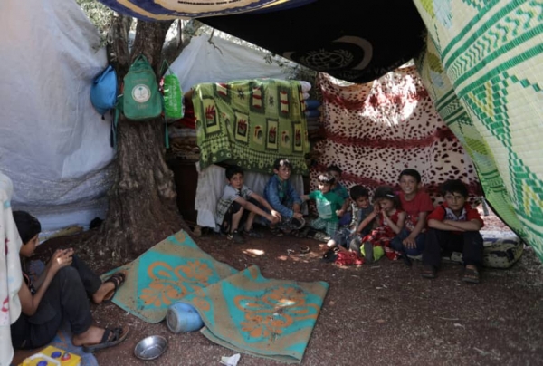 Displaced children sitting together in tent in camp in Idlib, Syria. 