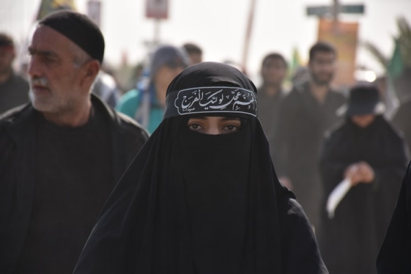 Woman wearing niqab walks among people   