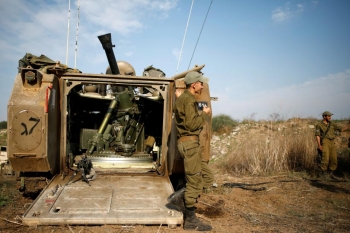 Soldati israeliani con un veicolo corazzato per il trasporto truppe, posizionati vicino al confine di Gaza, a sud di Israele. 