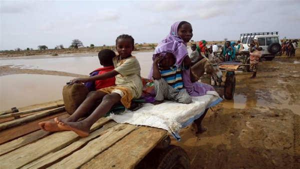 Internally displaced children and a woman sit on a car