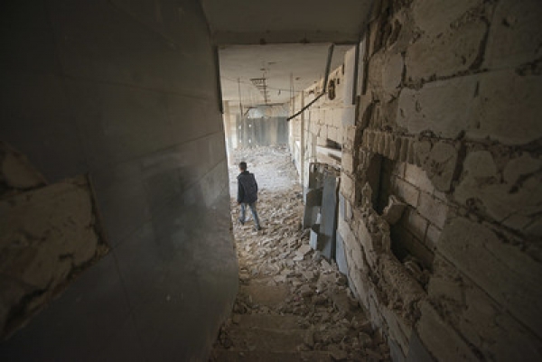 Un bambino cammina tra le macerie all&#039;interno di un edificio colpito da un attacco aereo, Siria, 13 novembre 2018