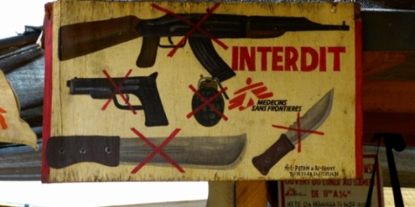 Cartello affisso davanti ad un Centro controllato da MSF, recante la scritta “Armi vietate”