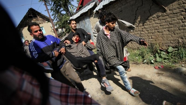 A group of Kashmiri men carrying a man injured during a gunfight in Kulgam