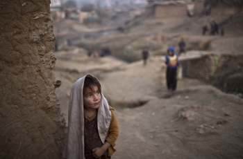 Una bambina afgana all&#039;entrata della casa in terracotta in un povero quartiere della periferia di Islamabad, Pakistan.