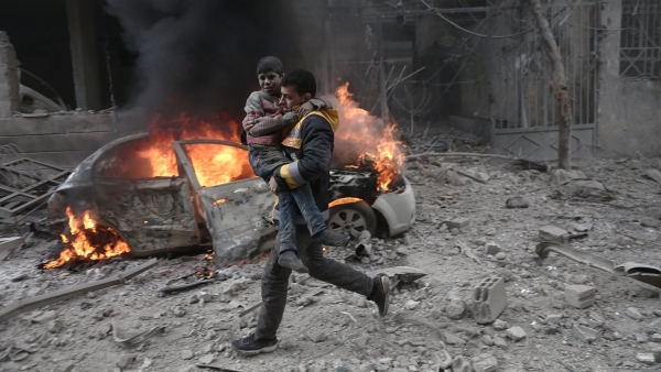 A Syrian paramedic carries a child injured in a bombing raid