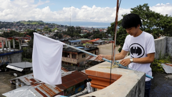 A young resident in Marawi displays a white flag on the rooftop of a house
