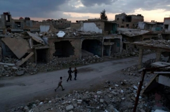 Syrian children walk past heavily damaged buildings in the rebel-held town of Douma on February 27, 2016. 