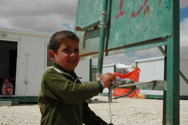 A Syrian refugee child uses a water kiosk in Za’atari camp, Jordan  