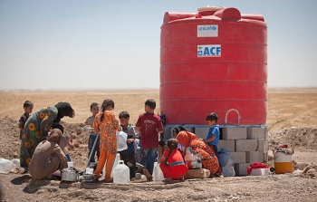 Women washing children at water tank, Iraq