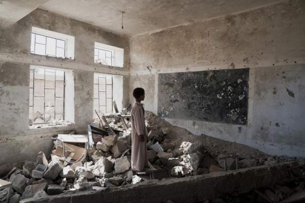 Student standing in the ruins of one of his former classrooms in Yemen