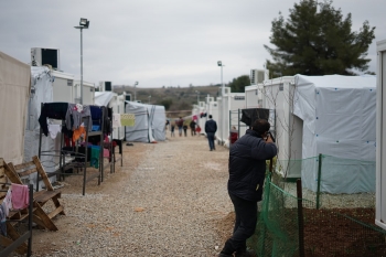 Campo rifugiati con persone sullo sfondo.