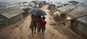  I rifugiati Rohingya di Myanmar restano uniti durante un acquazzone nell’insediamento di rifugiati di Kutupalong, in Bangladesh