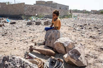 A child sits near a collection of defused rockets in Taiz governorate