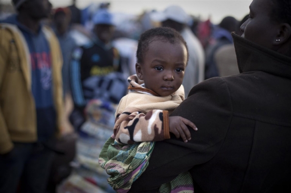Bambina in braccio alla madre, in fuga entrambe dalla Libia