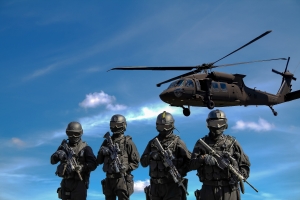 Four soldiers carry weapons near a helicopter   