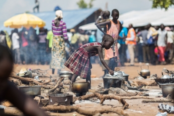 A young South Sudanese girl cooking food in a refugee camp in Uganda