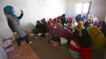 Afghan internally displaced school girls and women study at a class near their temporary homes on the outskirts of Kabul