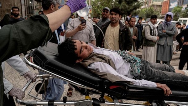 Medical personnel transport an injured adolescent via stretcher outside a hospital in Kabul