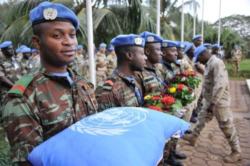 Caschi blu portano un cuscino e dei fiori per omaggiare i compagni caduti.