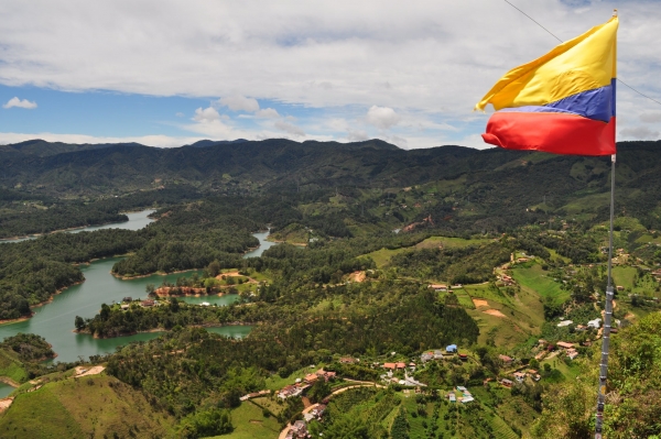 The flag of Colombia flies atop a rural river landscape