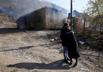 Residents hugging each other in front of a burning house in Kalbajar