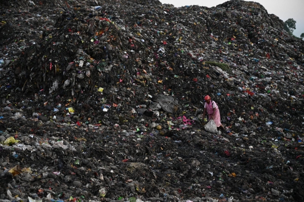 Woman picking up rubbish in a landfill