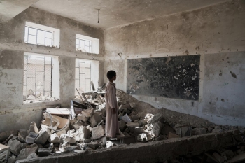 Studente tra le rovine di una delle sue ex aule in Yemen