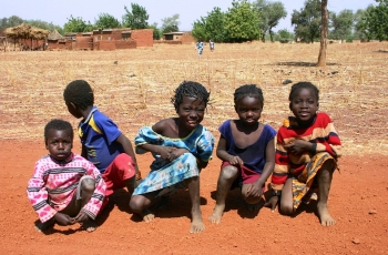 Cinque bambini del Burkina Faso accovacciati a terra  