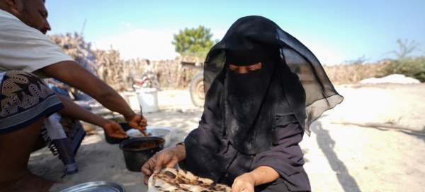 Woman cooking bread in a shelter, Yemen