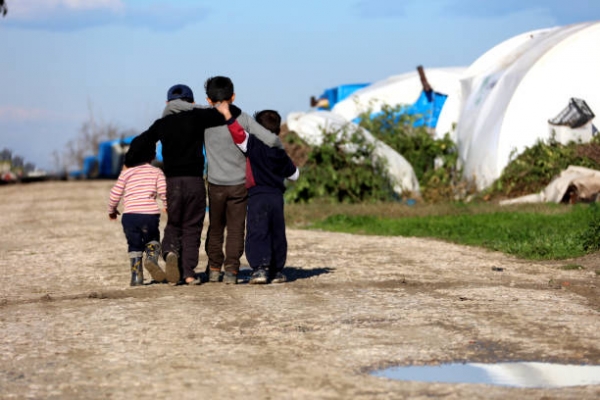 Un gruppo di bambini rifugiati che si abbracciano in un campo profughi Credits: 