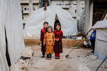 Three children in a camp for displaced people, Idlib, Syria