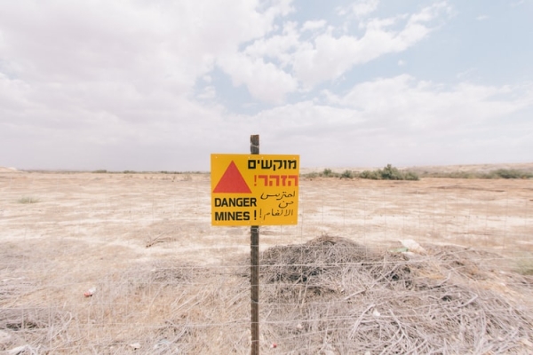 Sign warning of mines in front of a filed