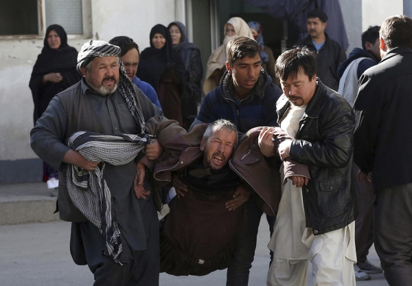 A distraught man is carried from the scene of the explosions in Kabul, Afghanistan.