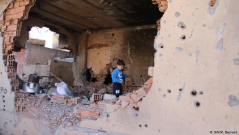 Un bambino curdo cerca di recuperare i propri averi dalla casa distrutta a Cizre