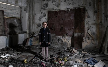 A pupil in eastern Ukraine stands amid the wreckage of her conflict-damaged schoolroom 