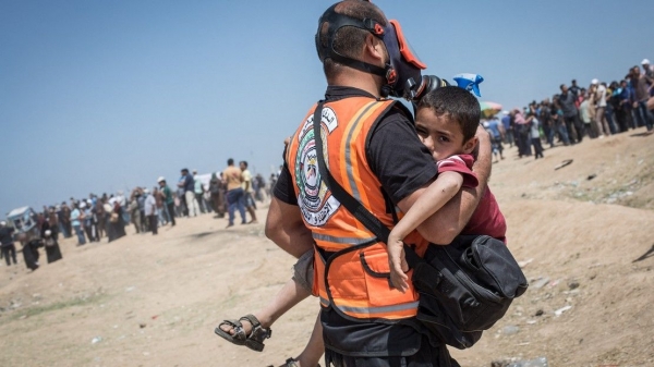 Humanitarian personnel taking a child to an ambulance, Gaza, 2018  