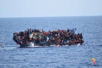 Migrants are seen on a capsizing boat before a rescue operation by Italian navy ships off the coast of Libya.