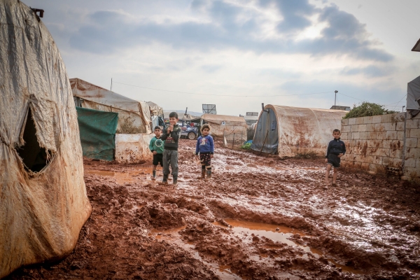 Children surrounded by mud in a camp in Idlib 