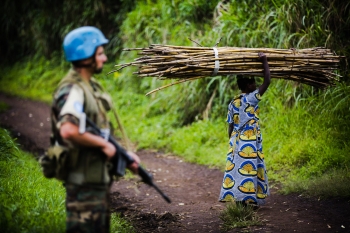 Donna attraversa una strada pattugliata dai peacekeepers