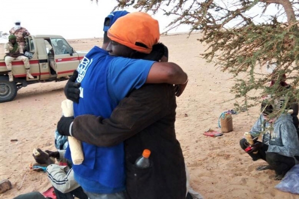 A migrant rescued after being abandoned by the driver hugs a IOM officer.